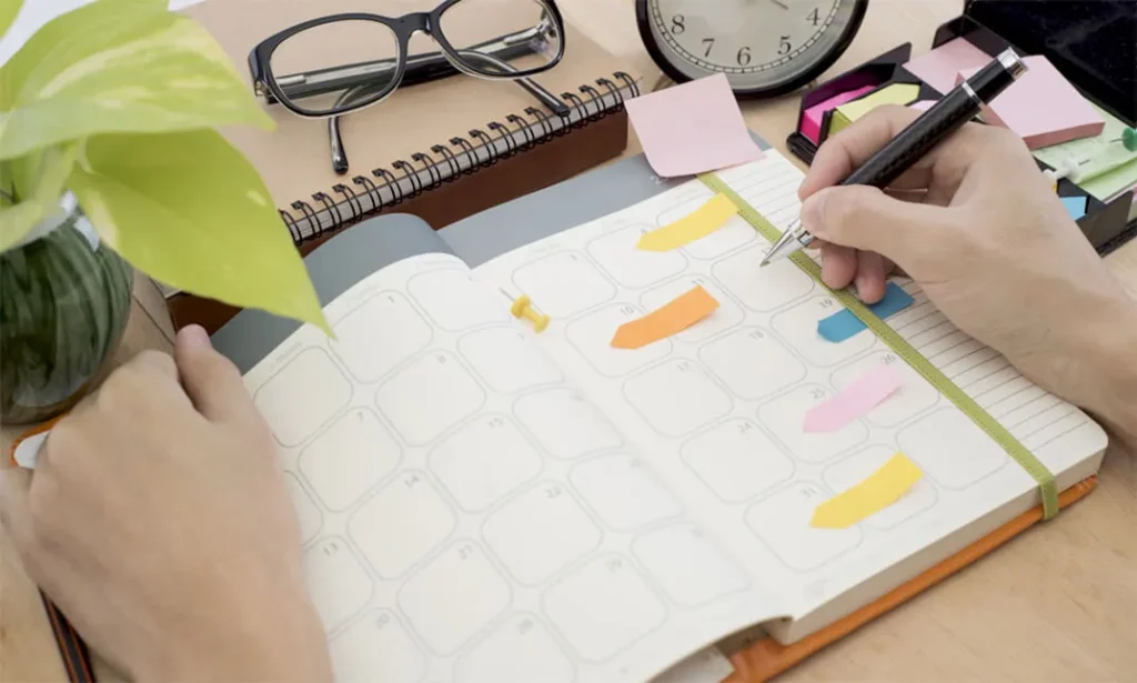 Image shows a well-organized workspace with a planner or schedule visible, showcasing a person engaged in a productive daily routine.